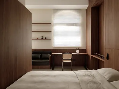 A modern minimalist bedroom with wooden walls, a bed, a desk, and a window with blinds.