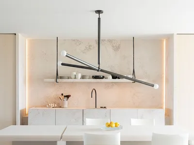 Modern minimalist kitchen with concrete countertops, white cabinets, and a dining table with white chairs and a black metal c