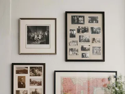 A living room with a collection of framed photographs on the wall and a wooden credenza with bottles and a tray of drinks.