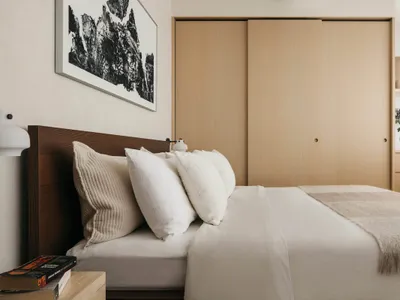 Bedroom featuring a minimalist design with wooden furniture and a metal headboard.