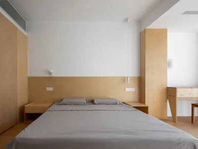 A minimalist bedroom with wood furniture and white walls.