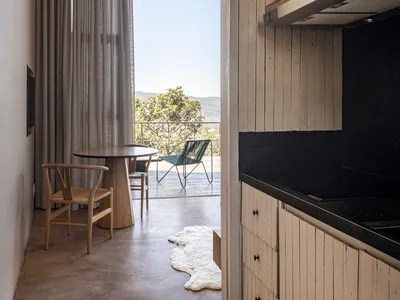 A minimalist residential kitchen featuring wood elements and a view of the outdoors through sheer curtains.