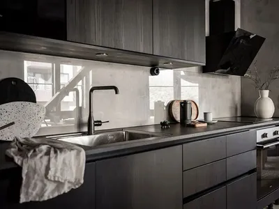 Kitchen with black wooden cabinets and a concrete backsplash.