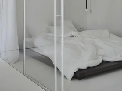 A minimalist bedroom with a bed in the center and a white curtain.