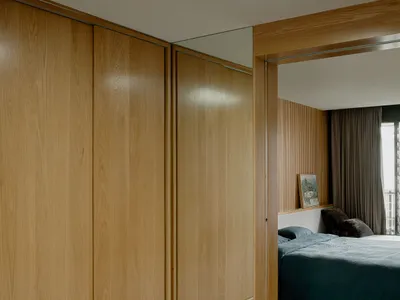 A modern minimalist bedroom featuring wooden furniture and glass elements.