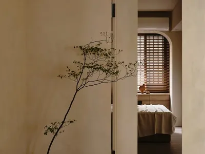 A minimalist bedroom with a bed, bedside table, and wooden floor and walls.