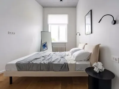 Modern minimalist bedroom with a bed, mirror, and side table