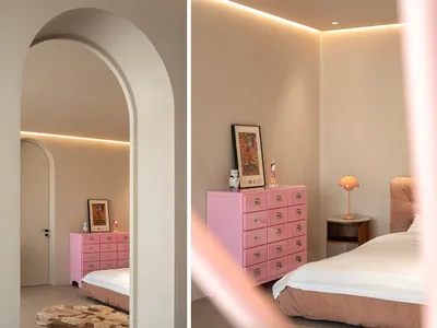 Minimalist bedroom with a pink metal dresser, white bedding, and a pink archway leading to a second room.