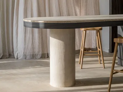 A minimalist lounge area with a textured concrete table and wooden stools.