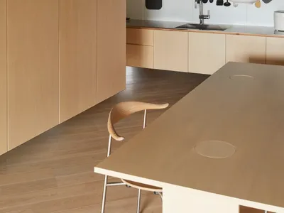A modern kitchen with wooden cabinets, countertops, and flooring, featuring minimalist design elements and a concrete ceiling