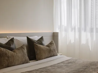 A modern minimalist bedroom with a bed, pillows, and sheer curtains.