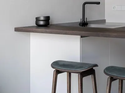 Modern kitchen with a wooden countertop, black faucet, and wall-mounted lamp.