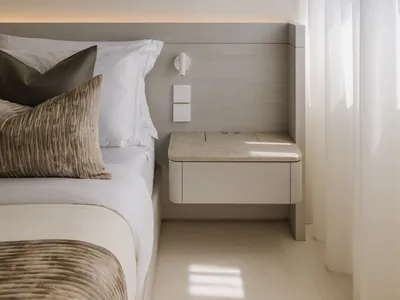 Modern minimalist bedroom with a wooden floating nightstand and white bedding.