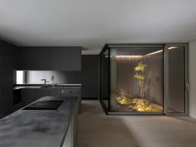 A modern minimalist kitchen with concrete countertops and glass cabinets.
