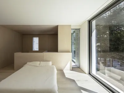 Modern bathroom with white walls and wood flooring, featuring a white bathtub and a large window.