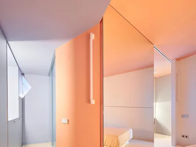 Modern minimalist bedroom featuring orange painted surfaces and large mirrors.