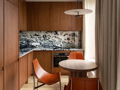 A modern kitchen with wooden cabinets, marble countertops, and metal chairs.