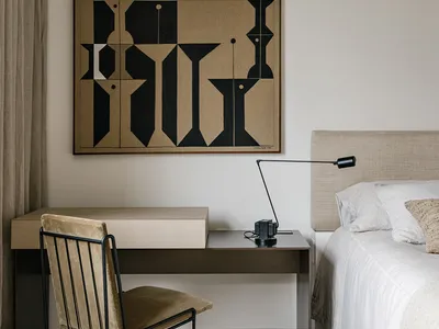 A minimalist bedroom with a wooden desk, metal chair, and fabric bedding.