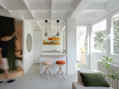 A modern, minimalist kitchen with white surfaces and an open-plan design.