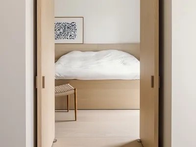 Minimalist bedroom with wooden furniture and white fabrics