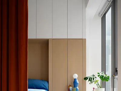 A minimalist bedroom with a white wood cupboard and blue bedding.