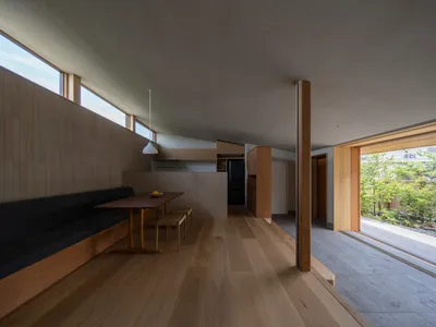 A modern kitchen with a wooden bench, concrete floor, and minimalist design elements.