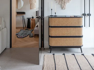 A minimalist bedroom featuring bohemian textiles and a woven chair.