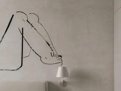 A minimalist bedroom featuring a bed with light-colored bedding, a concrete headboard, and a bedside table with a lamp.