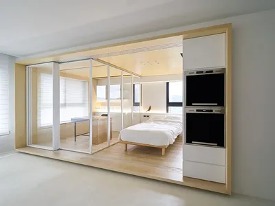 A modern bedroom featuring white walls, glass walls, and a wood frame.