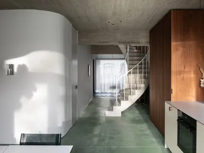 A modern kitchen with a concrete floor and a staircase leading to another level.