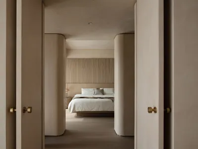 Modern, minimalist bedroom with neutral materials and a large bed.