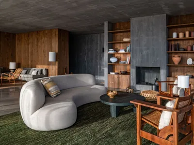 A modern industrial living room featuring a concrete fireplace, wooden shelves, and metal furniture.