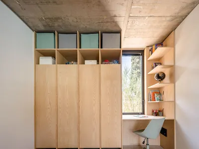 Modern home office with wooden shelves and a desk by the window.