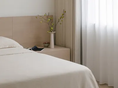 A minimalist bedroom with fabric curtains and wooden furnishings.