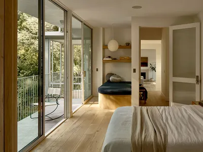 Minimalist bedroom with a white bed and wooden floor.