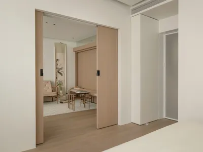 A minimalist bedroom featuring wooden furniture and a sliding door.