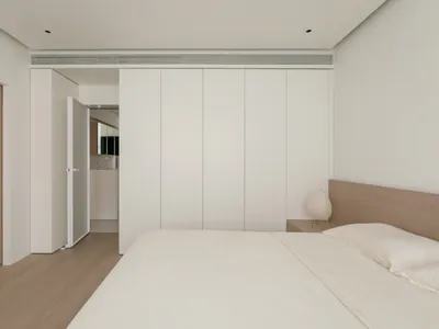 簡約白色臥室搭配木質家具，線條乾淨，設計元素簡潔。