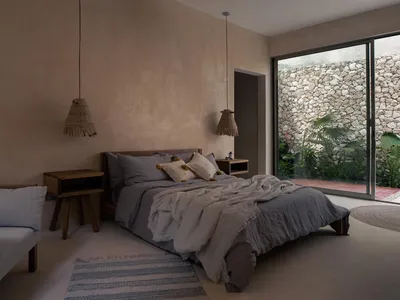 Minimalist bedroom with concrete walls and floor, featuring a bed with gray bedding and minimalistic decor.