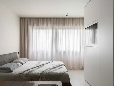 Modern minimalist bedroom featuring soft fabric curtains and sleek glass walls.