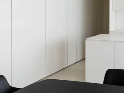 A minimalist bedroom featuring white cabinets against a white wall and floor.