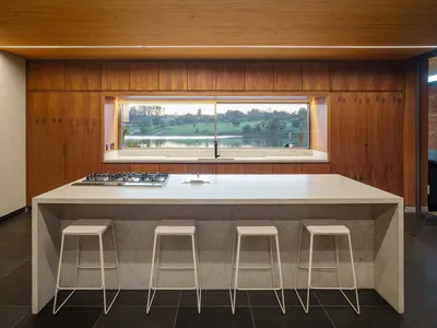 Modern kitchen with wooden cabinets, granite countertop, and a large window overlooking a scenic view.