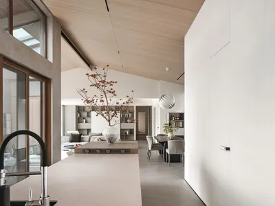 A modern minimalist kitchen with concrete walls, a wooden island, and a large window providing natural light.