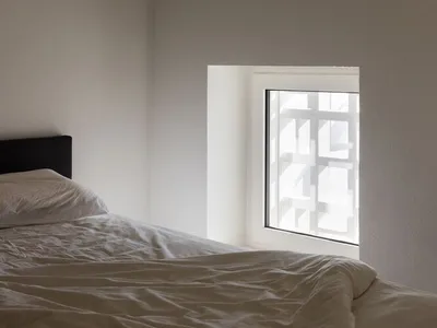 簡約臥室內擺放白色床鋪，並搭配質感壁紙。