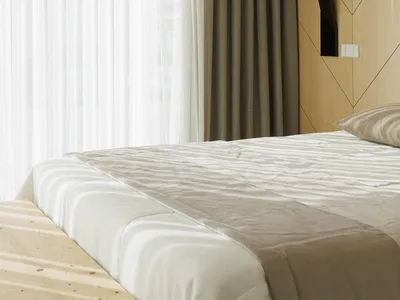Modern minimalist bedroom with a bed covered in a fabric comforter and a wooden headboard