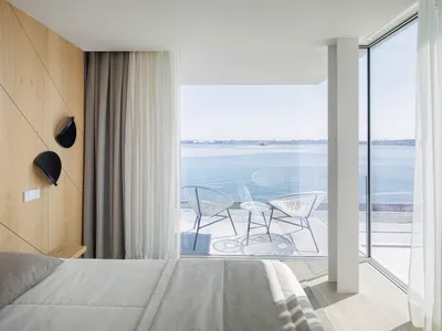 Modern minimalist bedroom with glass walls and a view of the sea.