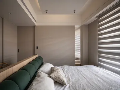 一間現代簡約臥室，搭配質感布料床頭板與木質家具，並設有玻璃門與柔和燈光。