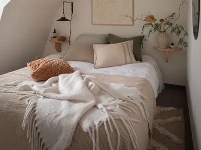 A cozy bedroom with a white bed, minimalist decor, and warm lighting.