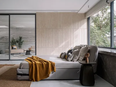 A modern bedroom featuring gray cushions and a yellow throw blanket on a gray sofa, with a view of green foliage outside.