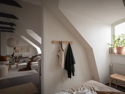 A minimalist bedroom featuring neutral tones and textiled fabrics hanging on a hook on the wall.