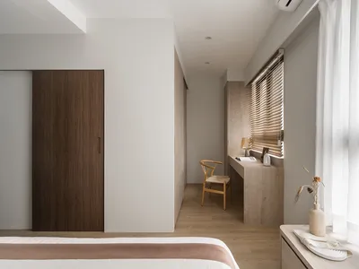 A minimalist bedroom featuring wooden furniture and materials, with soft lighting and a clean, uncluttered design.